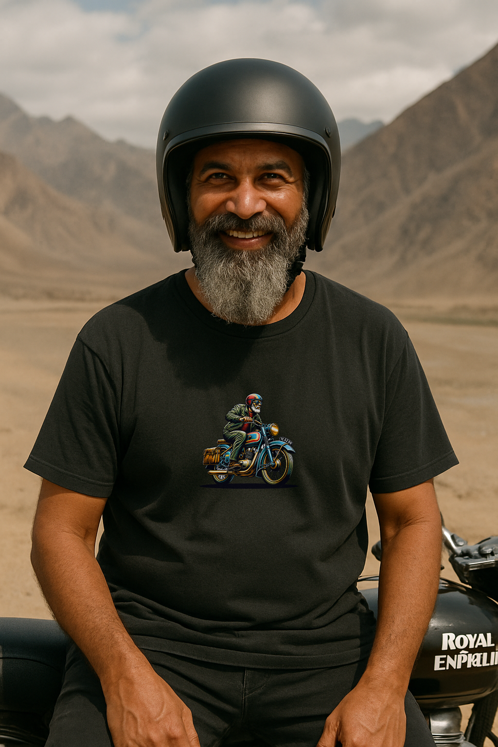 Man wearing a black helmet and black t-shirt with a motorcycle graphic, sitting on a motorcycle with mountains in the background.