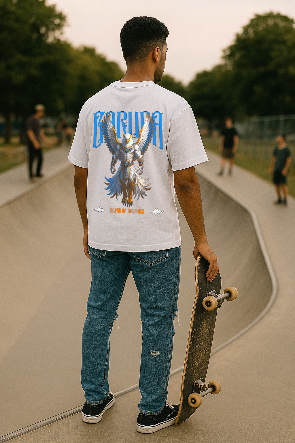 Person wearing a white t-shirt with a graphic design, holding a skateboard at a skate park.