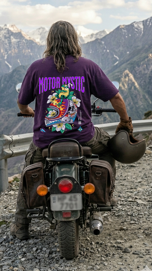 Person on a motorcycle with mountains in the background wearing a purple t-shirt with 'Motor Mystic' text.
