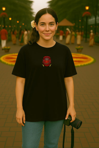 Woman wearing a black t-shirt with a red logo, standing in an outdoor setting with people and decorations.